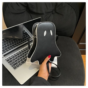 Detail of a black ghost-shaped crossbody bag with white piping and glittery eyes