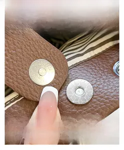 Close-up of high-quality magnetic snap closure on a brown pebble leather bucket bag