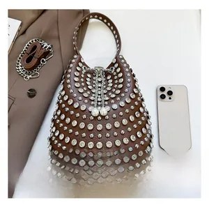 Detail of studded bucket bag with pearl drawstring and rhinestone accents next to a phone