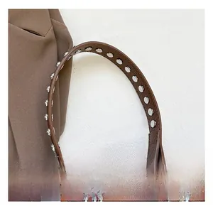 Detail of brown litchi leather handle with double row silver rivets and metal swivel hook
