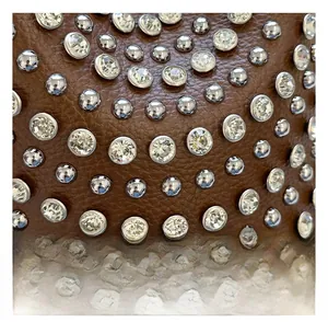 Detail of brown leather texture with silver rivets and sparkling crystal studs