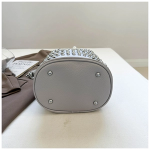 Detail of grey pebbled leather bucket bag bottom with silver protective metal studs