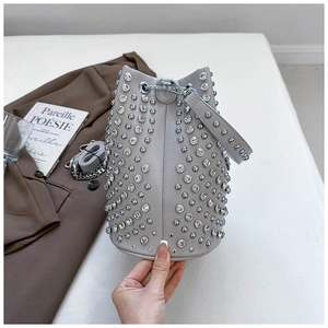 Detail of grey bucket bag with silver rivets and rhinestones on lychee leather texture