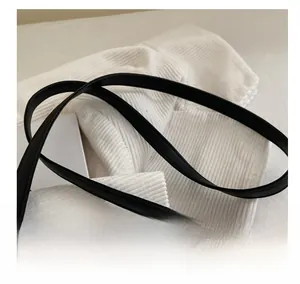 Detail of adjustable black leather shoulder strap with neat stitching on white fabric