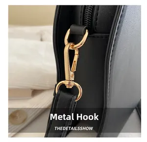 Close-up of premium golden metal hook and zipper on black leather shoulder bag