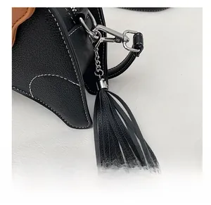 Detail of black PU leather bag with white stitching, silver hardware, and long fringe