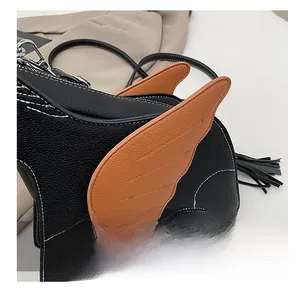 Close-up of litchi grain faux leather bag with brown wing patch and black tassel detail