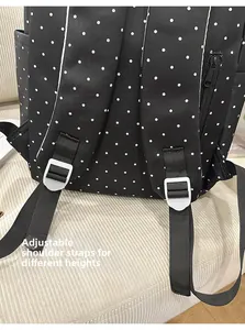 Detail of adjustable straps on black polka dot backpack showing functional buckles
