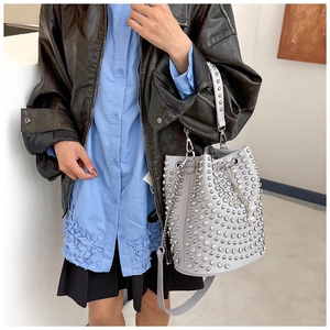 Detail of light gray rivet bucket bag with pearl chain and leather biker jacket style