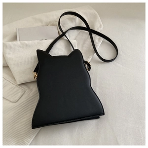 Detailed top view of black cat-shaped shoulder bag on white corduroy fabric texture