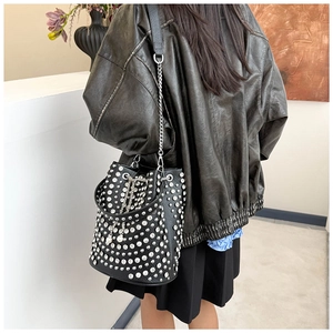 Detail of black leather bucket bag with silver studs and elegant pearl drawstring chain