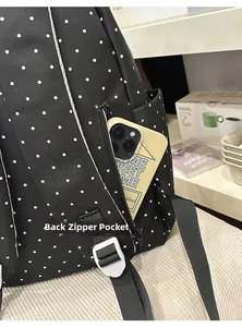 Detailed view of back hidden anti-theft zipper pocket on black polka dot backpack