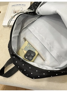 Macro view of polka dot backpack interior showing layered pockets and zipper compartment
