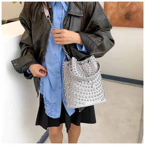 Detail of grey bucket bag featuring silver rivets and elegant pearl pendant accessory