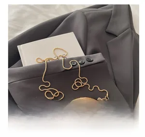 Detailed close-up of golden crescent bag with mirror finish and metallic ball chain