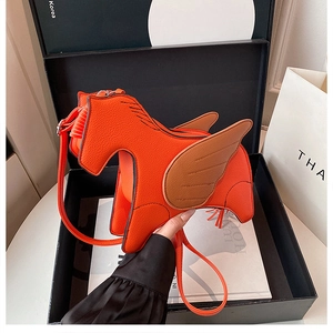 Detailed close-up of orange horse-shaped crossbody bag in a gift box with pebble leather
