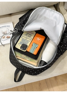 Flat lay of spacious black polka dot backpack interior filled with books and daily essentials
