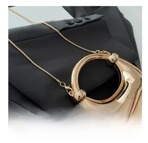 Macro view of golden crescent acrylic bag with circular handle and fine metal chain link