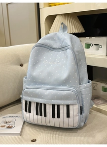 Detail of light blue polka dot backpack featuring piano key pocket and music embroidery