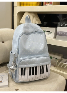 Detail of blue polka dot backpack with piano keys and star charm on a beige sofa