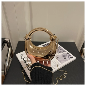 Close-up of golden crescent acrylic mini evening bag with round handle and metal chain