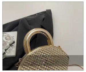Detail view of round gold crystal clutch featuring beaded texture and metal handle