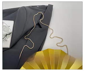 Detailed close-up of golden snake bone chain strap on stylish fan-shaped acrylic evening bag
