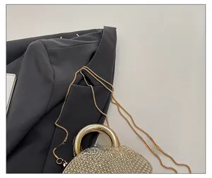 Detail of luxury gold evening bag with rhinestones, metal ring handle and chain strap
