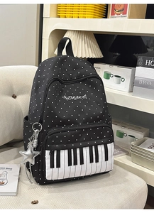 Detail of music themed backpack featuring piano key pocket and silver star charm