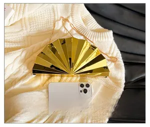 Detail showing fan-shaped gold acrylic evening clutch with fine metal chain and sizing reference