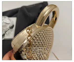 Macro detail of heart-shaped acrylic evening bag with golden beads and round handle