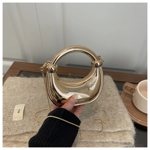 Detail of a gold crescent moon acrylic bag with polished mirror finish and chain strap