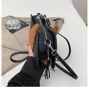 Detail of black pebbled leather crossbody bag with brown wing decor and silver hardware