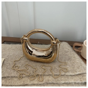 Close-up of golden crescent moon evening bag with mirror finish and circular handle