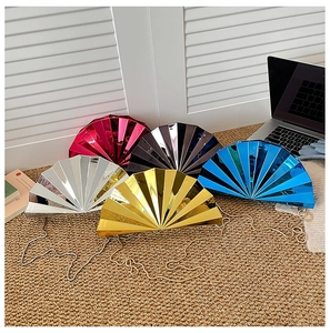 Macro shot of fan-shaped evening clutch bags in metallic colors with chain straps