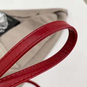 Detailed close-up of the red leather shoulder strap with premium stitching on round bag