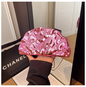 Dettaglio borsa a mano rosa metallizzata con texture a pieghe e tracolla a catena oro