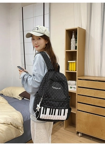 Detail view of black polka dot backpack with piano key design on a female model