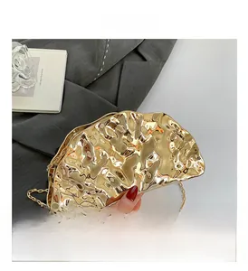 Detail of golden metallic evening shell bag with liquid texture and thin chain