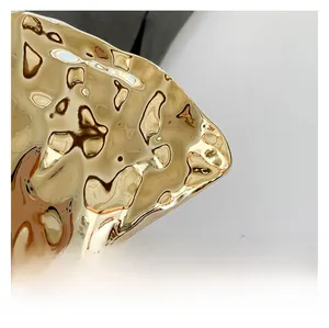 Macro detail of the golden shell bag featuring a luxury ice-cracked water ripple texture