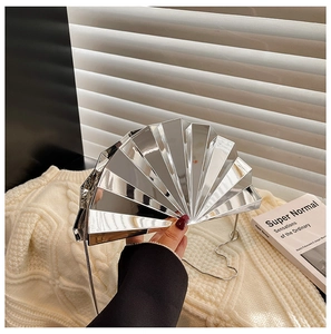 Macro detail of fan-shaped silver metallic clutch bag with mirror finish and chain