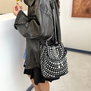 Fashionable black leather bucket bag with silver rhinestones and chain strap on model
