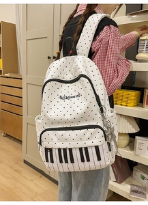 Detail of white polka dot backpack with piano key design and music print on front pocket
