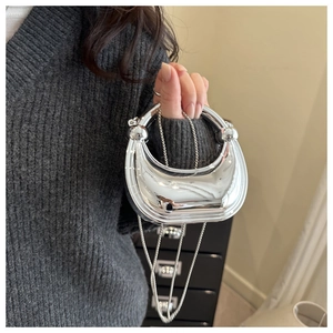 Silver crescent clutch bag featuring a round metal handle and elegant chain strap detail
