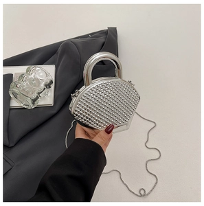 Detail of silver shell-shaped evening bag with rivet texture and metal top handle