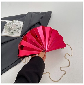 Detail of a fan-shaped acrylic evening clutch bag in metallic rose red with gold chain