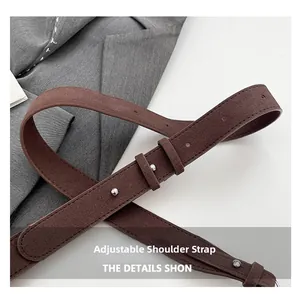 Close-up of adjustable brown suede shoulder strap with silver metal buckle and stitching