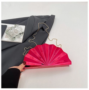 Macro detail of the fuchsia fan-shaped clutch bag with golden chain and metallic texture