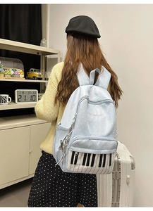 Close-up of a blue polka dot backpack featuring piano key print and a star charm detail