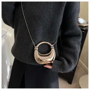 Detail view of mini gold crescent moon clutch with metallic mirror finish and chain